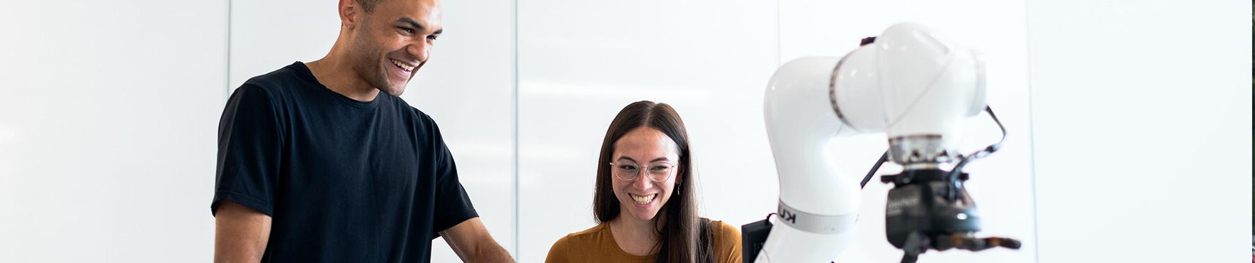 smiling students trying out a mechanical device